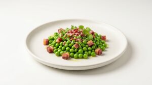 Plato de guisantes con jamón emplatado de forma moderna, con taquitos de jamón ibérico por encima