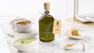 Botella de AOVE RH Gourmet sobre mármol blanco junto a tres usos culinarios: crudo, guiso y fritura.